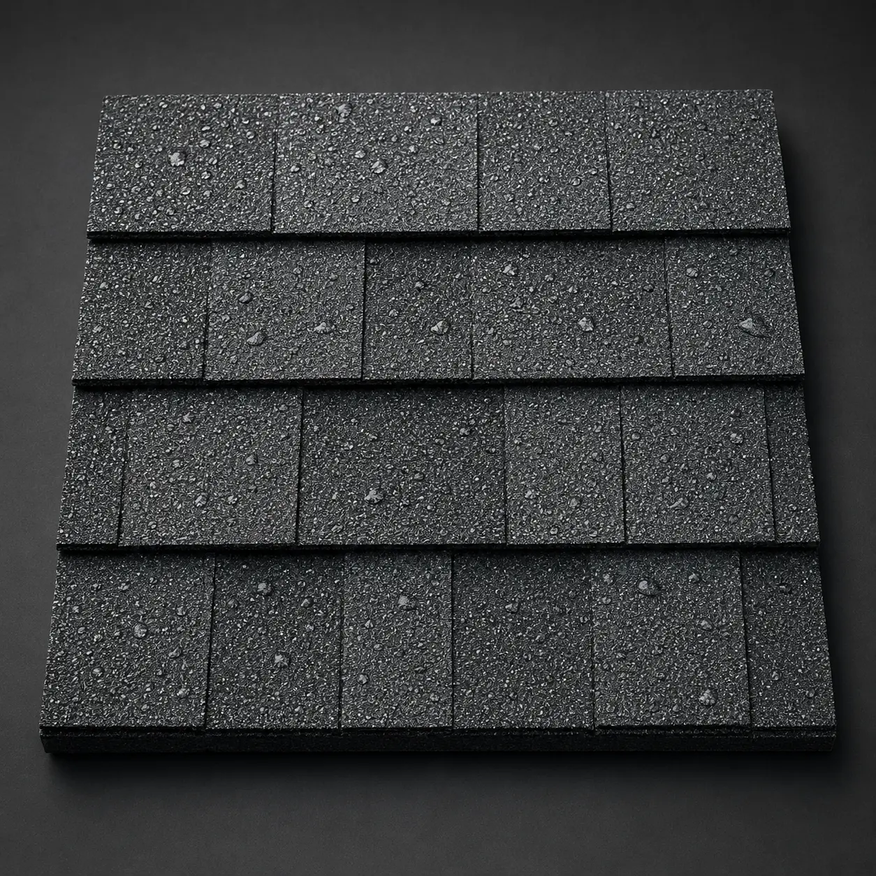 Close-up product photograph of wet charcoal architectural asphalt shingles